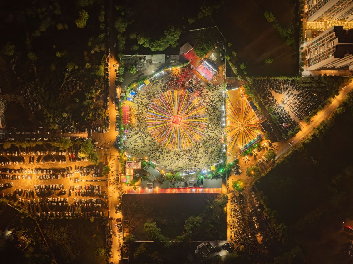 Aerial night view of the PYC Navratri ground: thousands of khelaiyas around radial ribbons of light